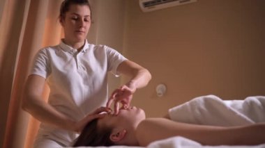 Kadın güzellik uzmanı bir kadın müşteriye yüz kaslarını masaj yapar. Vücut bakımı, cilt bakımı, sağlık, sağlık, güzellik tedavi konsepti.