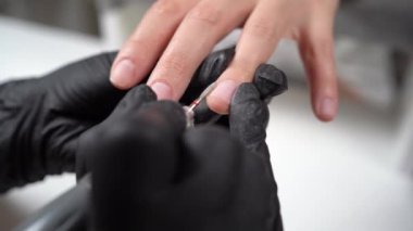 Kadın usta kuafördeki manikürün tırnak etlerini temizlemek için elektrikli makine kullanıyor. Donanım manikürü. El bakımı konsepti. Manikürcü bir kadın, modemiyle tırnaklarını temizliyor..