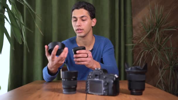 Treinamento de vídeo para fotógrafos iniciantes, cursos online. Um homem muçulmano olha para a câmera e fala sobre diferentes tipos de lentes. Conceito de negócio info e venda de cursos on-line. — Vídeo de Stock
