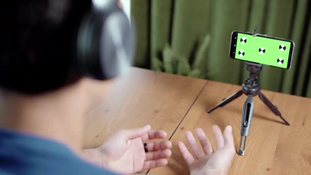 Człowiek wykonujący połączenie wideo na zielonym ekranie smartfona aparat z markerów śledzących. Facet rozmawia i słucha podczas wideo czatu ze znajomymi lub kolegami. Widok ekranu telefonu komórkowego przez — Wideo stockowe