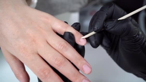 Manicure procedure met behulp van een bamboe stok in een schoonheidssalon. Handverzorgingsconcept. Vrouwelijke manicure meester reinigt nagels voor een klant — Stockvideo