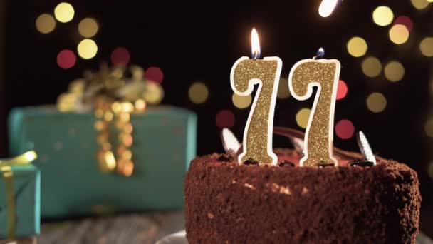 Číslo sedmdesát sedm narozeninové svíčky na sladkém dortu na stole, 77. narozeniny. Oheň ze zapalovače, sfoukni sváteční svíčku. — Stock video