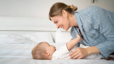 Anne 30 yaşında, küçük oğluyla yatakta oynuyor, çocuk sabah annesiyle yatak odasında, çocuk bakımı, mutlu annelik ve çocukluk kavramı.