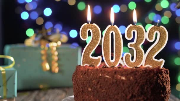 新年快乐。2032年，桌上放着一支甜饼，上面放着一支金色的蜡烛，号码是二千三十二个。打火机的火，吹灭假日的蜡烛. — 图库视频影像