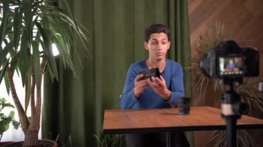 Profesyonel bir fotoğrafçının bloğu. Genç yakışıklı bir Arap ya da Müslüman adam fotoğraf ekipmanları hakkında bir video kaydediyor. Lenslerin türünü gösteriyor. Evde video stüdyosu.