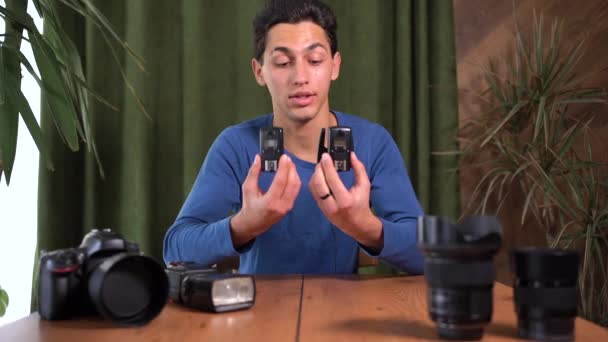 Відео-посібник про те, як працювати з радіосинхронізаторами для фотоспалаху. Молодий привабливий арабський чоловік знімається в камері. Онлайн-учитель, наставник. — стокове відео