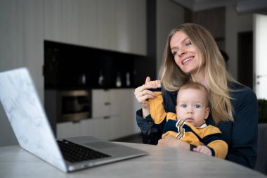 Bebeği olan anne uzaktan çalışıyor, video konferans ya da zoom çağrısı, web kamerası ile arkadaşlarla iletişim, anne evde dizüstü bilgisayarla doğum izninde.