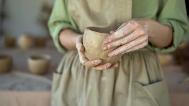 女性の陶芸家の手を閉じて彼女の手で土鍋を彫刻。陶芸家は、手作りの陶器を作るために生の陶器と仕事をします。技能及び小規模事業の概念 — ストック動画