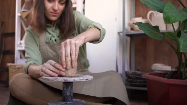 Vrouwelijke pottenbakker beeldhouwt een stuk klei aan een tafel. Een vrouw maakt een keramisch object. Aardewerk, handwerk en creatieve vaardigheden in een kunststudio. handen van de master close-up. — Stockvideo