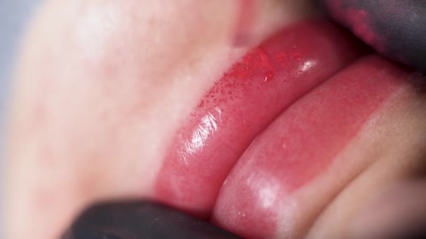 Крупный план, процесс нанесения красящего пигмента на губы женщины, татуировка губы в салоне красоты, постоянный макияж губ — стоковое видео