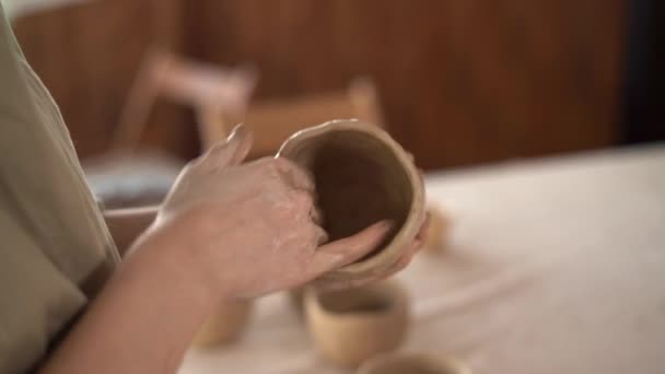 Κοντινό πλάνο γυναίκες αγγειοπλάστες χέρι γλυπτική ένα πήλινο δοχείο με τα χέρια της. Γυναικεία κεραμική με ακατέργαστα πήλινα σκεύη, δημιουργώντας χειροποίητη κεραμική. Ικανότητα και έννοια των μικρών επιχειρήσεων — Αρχείο Βίντεο