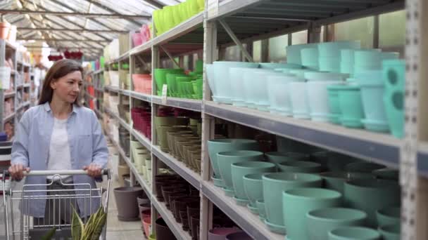 Gros plan de la femme qui choisit des pots en céramique pour les plantes d'intérieur dans un centre de jardin. Femme achetant pot de greffe de plante à la maison dans l'entrepôt — Video