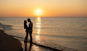 Egy szerelmes pár romantikus pillanatokat él át naplementekor a parton. Fiatal szerelmesek a nyári szünetben. a szerelem vagy a nászút fogalma. Csókold meg a sziluettet naplementekor. Másolás. banner