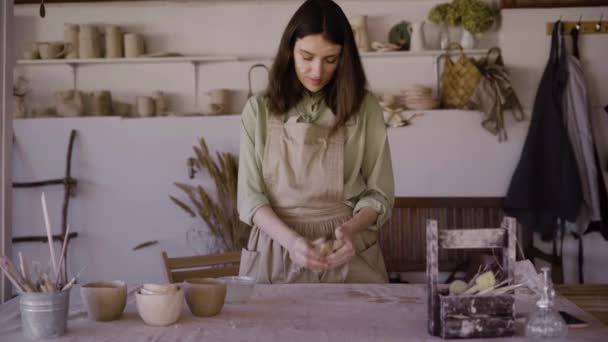 Vrouwelijke pottenbakker beeldhouwen klei pot met haar handen. Een keramist werkt met rauw aardewerk om handgemaakt aardewerk te maken. Vaardigheid en concept voor kleine bedrijven — Stockvideo