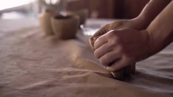 陶芸家の女性の手は、白い粘土の柔らかくて湿った部分を形成します。手作りの鍋を作るための粘土材料の準備。作られる過程でセラミックがクローズアップされる。粘土手彫刻 — ストック動画