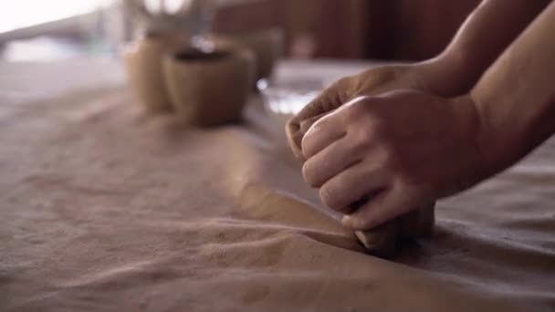 As mãos femininas de um oleiro amassam e formam uma parte suave e molhada de barro branco. Preparação de material de argila para fazer panelas artesanais. Cerâmica no processo de ser feito close-up. Escultura mão argila — Vídeo de Stock