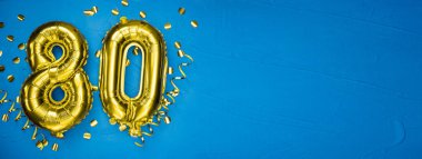 Mavi beton arka planda seksen numaralı sarı folyo balonu. 80 'inci yazılı doğum günü ya da yıldönümü kartı. Yıldönümü kutlaması. Pankart.