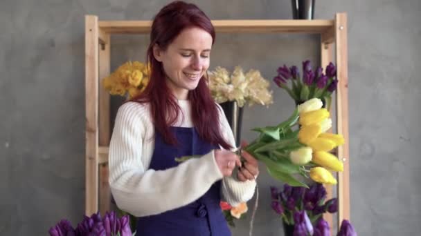 . florista feminina em um avental está concentrada em uma loja de flores. Estúdio de design floral, fazendo decorações e arranjos. Entrega de flores, criação de ordem. Buquê de tulipas amarelas — Vídeo de Stock