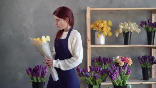 Kwiaciarnia właściciel firmy w pracy, ładna młoda dama robi modny nowoczesny bukiet tulipanów. Zakłada bukiet i trzyma ręce za plecami. pojęcie zmęczenia i przepracowania w miejscu pracy. — Wideo stockowe