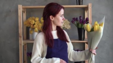 Çiçekçi işyeri sahibi, modern lale buketi yapan genç ve güzel bir bayan. Bir çiçekçinin işyeri. Sevdiğin biri için hediye hazırlıyorsun. Bahar çiçeği konsepti.