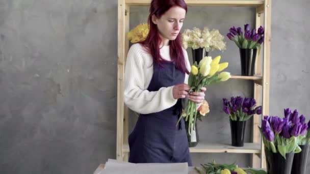 Европейская концепция цветочного магазина. Девушка-флористка в фартуке создает красивый букет желтых тюльпанов. Прекрасный свежий букет. Образование, мастер-классы и курсы флористики. — стоковое видео