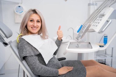 Dişçi kliniğini ziyaret et. Diş muayenesi ve dişçi muayenesi sırasında genç ve pozitif bayan müşterinin gülümsemesi. Boşluğu kopyala.