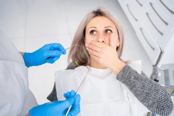 The concept of medicine and dental health, modern dentistry, caries treatment in the clinic, a woman sitting in a dental chair, fear of a dentist