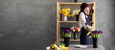 Satılık bir kompozisyon yaratmak için güzel çiçek laleleri kullanan genç bir çiçekçinin portresi. Kadın işyeri sahibi telefonla sipariş alır. Boşluğu kopyala.