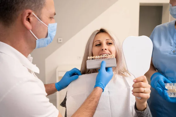 Lekarz Dentysta Niebieskich Rękawiczkach Trzymający Stół Odcieni Zębów Wybierający Odpowiedni — Zdjęcie stockowe