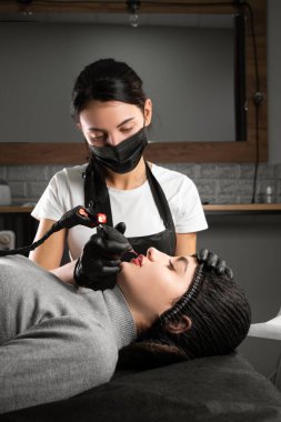 Kalıcı makyaj. Spa güzellik tedavileri. Genç bayan. Usta dudaklara dövme yaptırır. Profesyonel yüz mikro pateni. Kadın kozmetoloji aygıtı. Dermatoloji