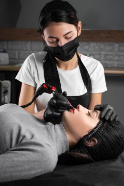 Kalıcı makyaj. Spa güzellik tedavileri. Genç bayan. Usta dudaklara dövme yaptırır. Profesyonel yüz mikro pateni. Kadın kozmetoloji aygıtı. Dermatoloji. Boşluğu kopyala.