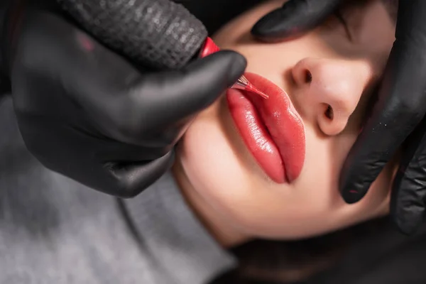 在使用永久化妆品的过程中 女性嘴唇肿胀的特写 脸上有纹身 嘴唇上有微小色素 专业的面部微珠 女性化妆品器具 — 图库照片