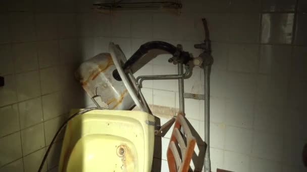 Tvättstuga i en förstörd byggnad, trasig keramikdiskbänk. POV med ficklampa i en förstörd byggnad. — Stockvideo