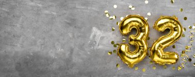 Sarı folyo balon numarası, 32 numara beton arka planda. 32 yazıtlı doğum günü kartı. Yıldönümü konsepti. Yıldönümü, doğum günü, yeni yıl kutlaması için. afiş, boşluğu kopyala.
