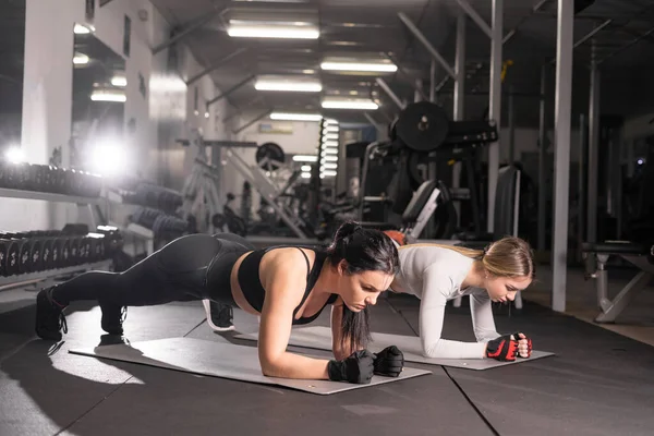 Duas Jovens Mulheres Atraentes Estão Envolvidas Treinamento Prancha Exercícios Ginástica — Fotografia de Stock