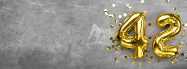 Sarı folyo balon numarası, 42 numara beton arka plan. 42. yazıyla birlikte tebrik kartı. Yıldönümü konsepti. Yıldönümü, doğum günü, yeni yıl kutlaması için. afiş, boşluğu kopyala.