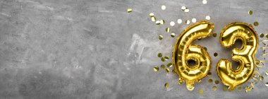 Sarı folyo balon numarası, arka planda 63 numara. Altmış üç yazılı tebrik kartı. Yıldönümü konsepti. Yıldönümü, doğum günü, yeni yıl kutlaması için. afiş, boşluğu kopyala.