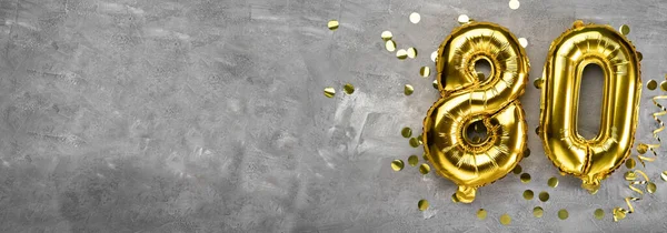 Sarı folyo balon numarası, 80 numara beton arka planda. Üstünde 80 yazan tebrik kartı var. Yıldönümü konsepti. Yıldönümü, doğum günü, yeni yıl kutlaması için. afiş, boşluğu kopyala.