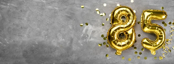 Sarı folyo balon numarası, beton arka planda 85 numara. Üzerinde 85 yazan tebrik kartı var. Yıldönümü konsepti. Yıldönümü, doğum günü, yeni yıl kutlaması için. afiş, boşluğu kopyala.