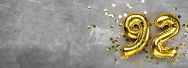Beton bir arka planda 92 numaralı sarı folyo balonu. 92 yazısıyla birlikte tebrik kartı. Yıldönümü konsepti. Yıldönümü, doğum günü, yeni yıl kutlaması için. afiş, boşluğu kopyala.