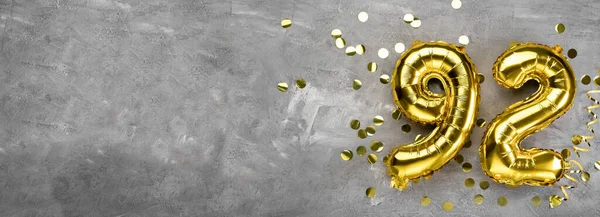 Beton bir arka planda 92 numaralı sarı folyo balonu. 92 yazısıyla birlikte tebrik kartı. Yıldönümü konsepti. Yıldönümü, doğum günü, yeni yıl kutlaması için. afiş, boşluğu kopyala.