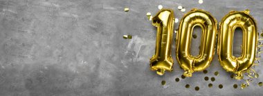 Sarı folyo balon numarası, beton arka planda 100 numara. Üstünde 100 yazılı tebrik kartı var. Yıldönümü konsepti. Yıldönümü, doğum günü, yeni yıl kutlaması için. afiş, boşluğu kopyala.