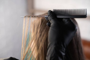 Kuaför saçı boyar, saç tellerini boyama ya da renklendirme için ayırır. Esmer. Güzellik salonuna geldi..