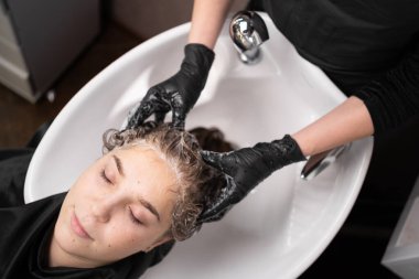 Güzel bayan rahatla ve saçını şampuan ve masajla yıkarken rahatla. Saç stili, güzellik ve moda konsepti olan bir kuaför salonu. Beyaz kadın kuaförde