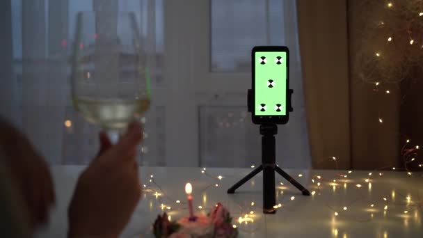 Layar hijau dan kunci kroma smartphone. Konsep kencan onolan. wanita duduk di rumah di malam hari dengan segelas anggur dan membuat panggilan video. — Stok Video