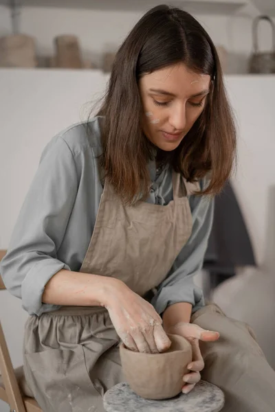 手作りの陶器の製作です 陶芸スタジオの女性陶芸家は粘土で鍋を形成します 女性は手作りのボウルを彫刻します コピースペース — ストック写真