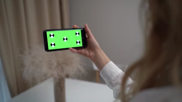 Mujer hablando en videollamada en línea con pantalla verde en la mesa en casa. Atractiva hermosa chica en los auriculares disfruta de la conversación en línea en el teléfono móvil por la noche en casa — Vídeos de Stock