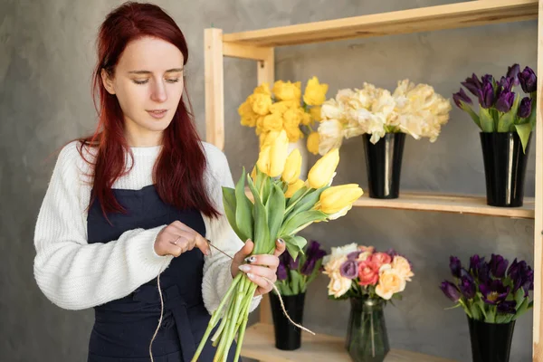 European flower shop concept. A female florist creates a beautiful bouquet of spring tulip flowers. Beautiful fresh bouquet. Education, master classes and floristry courses. Flower delivery.