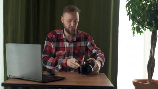 Professionele mannelijke fotograaf opent de cover van de camera, neemt een flash drive en begint met het uploaden van gegevens naar een laptop. — Stockvideo