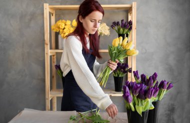 Çiçekçi kadın çalışıyor. Genç ve güzel bir bayan farklı lalelerden bir buket yapar. Anneler Günü ya da Sevgililer Günü için harika bir hediye. Boşluğu kopyala